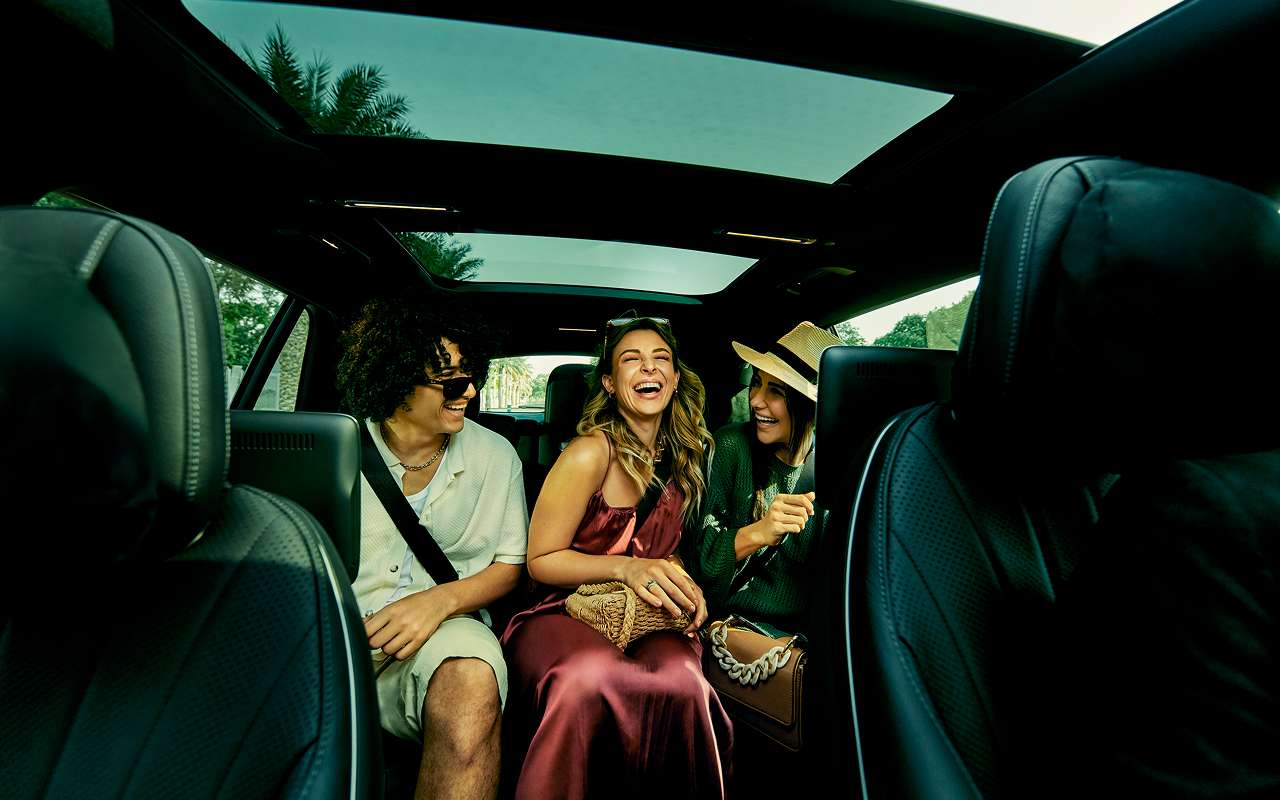 Friends laughing together in the back seat of a luxury SUV