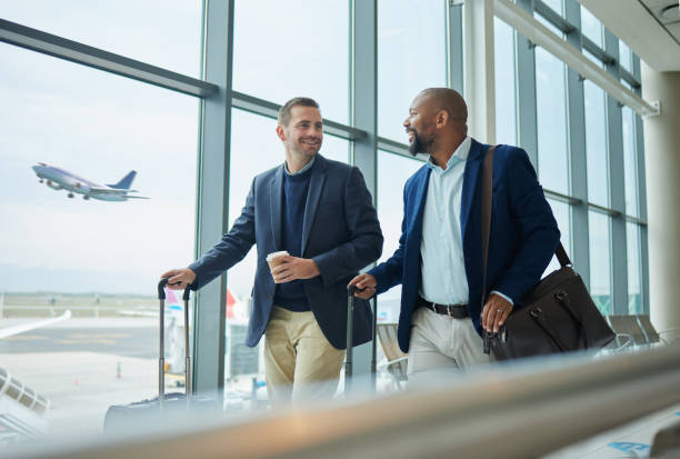 Two business travelers with luggage walking through an airport terminal