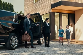 Family arriving at a modern home with a black SUV and chauffeur