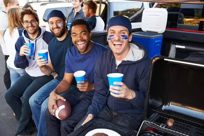 Friends tailgating with a football before a game